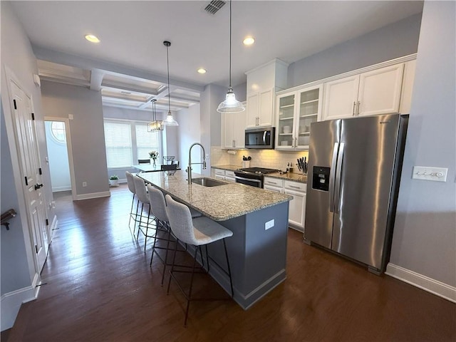 kitchen featuring a sink, stainless steel appliances, baseboards, and a center island with sink