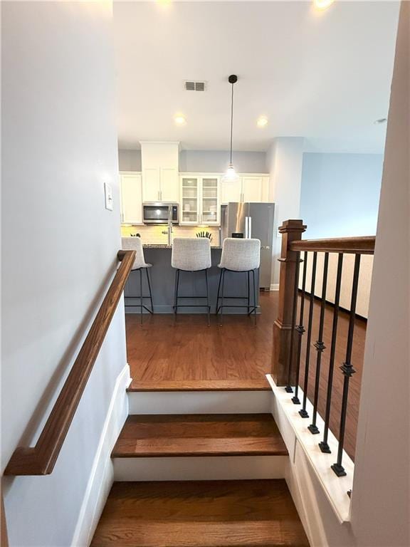staircase with recessed lighting, visible vents, and wood finished floors