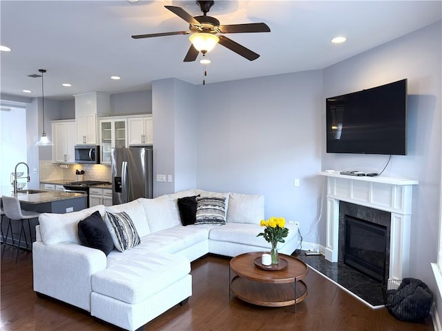 living room featuring a high end fireplace, a ceiling fan, dark wood-type flooring, and recessed lighting