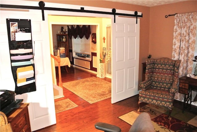 sitting room featuring a barn door, a textured ceiling, and dark hardwood / wood-style floors