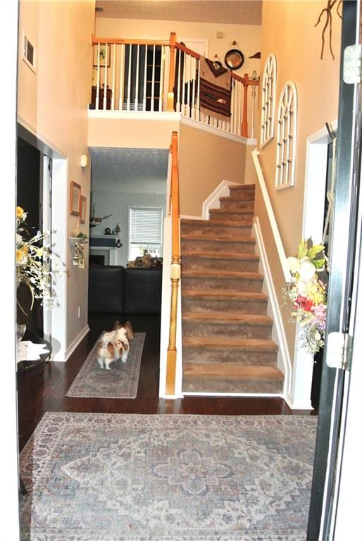 stairs featuring a towering ceiling and hardwood / wood-style flooring