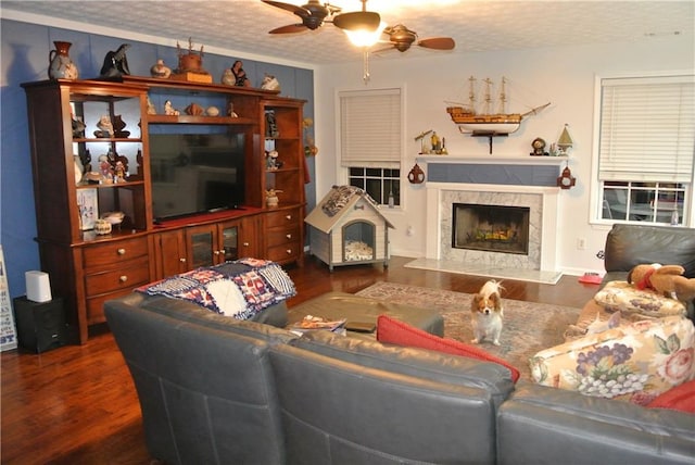 living room featuring a textured ceiling, dark hardwood / wood-style flooring, ceiling fan, and a premium fireplace