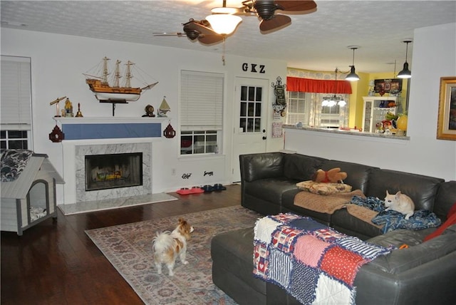 living room featuring a high end fireplace, a textured ceiling, dark wood-type flooring, and ceiling fan