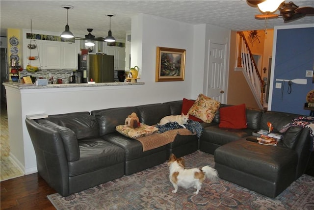 living room with ceiling fan, a textured ceiling, and dark hardwood / wood-style floors