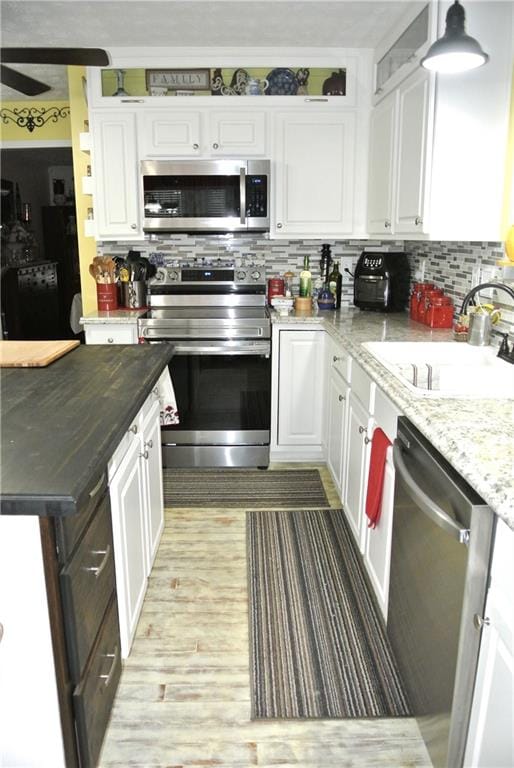 kitchen with appliances with stainless steel finishes, backsplash, sink, and white cabinetry