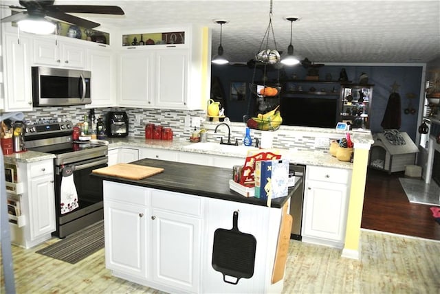 kitchen with ceiling fan, white cabinets, pendant lighting, electric range, and a center island