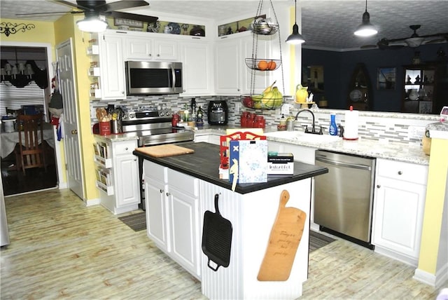 kitchen with pendant lighting, white cabinetry, ceiling fan, and appliances with stainless steel finishes