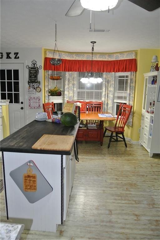 kitchen featuring ceiling fan with notable chandelier, hanging light fixtures, and light hardwood / wood-style floors