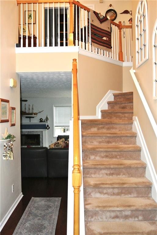 stairs with hardwood / wood-style flooring and a towering ceiling