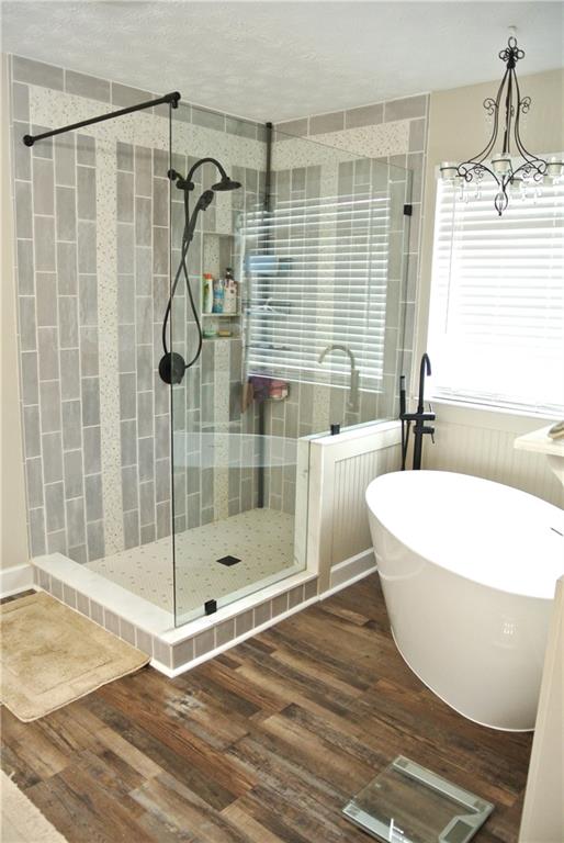 bathroom with an inviting chandelier, hardwood / wood-style flooring, and shower with separate bathtub