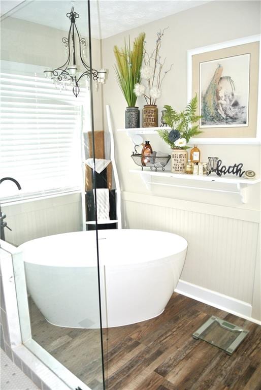 bathroom featuring a notable chandelier, a tub to relax in, and hardwood / wood-style floors