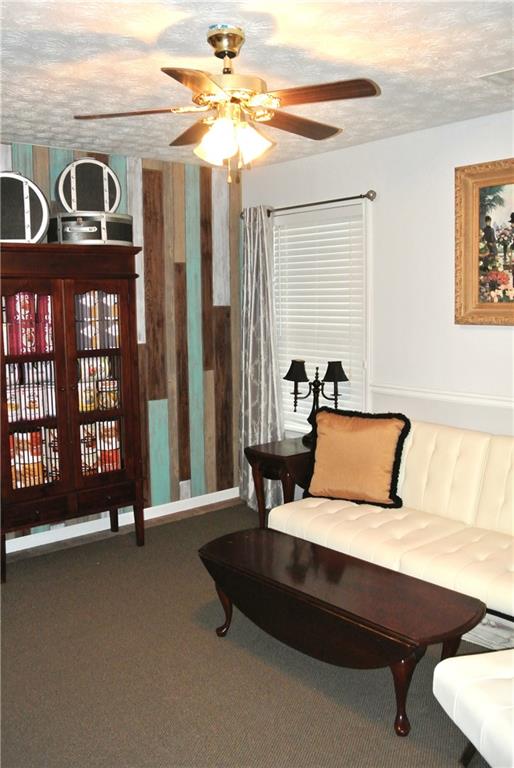 interior space featuring dark colored carpet, ceiling fan, and a textured ceiling