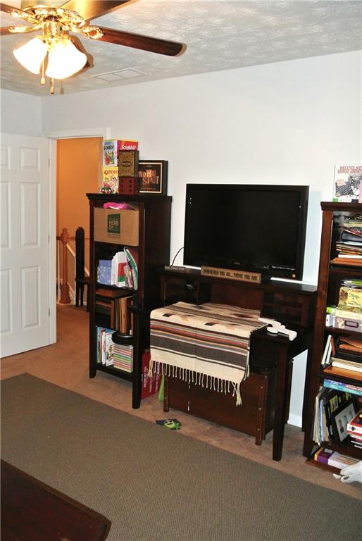 misc room featuring a textured ceiling, carpet flooring, and ceiling fan