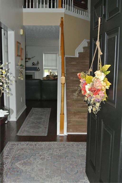 entryway featuring a towering ceiling and dark wood-type flooring