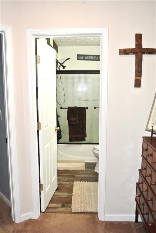 bathroom featuring shower / washtub combination, toilet, and hardwood / wood-style flooring