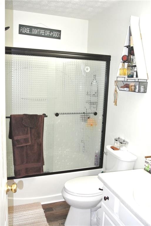 full bathroom with wood-type flooring, a textured ceiling, combined bath / shower with glass door, vanity, and toilet