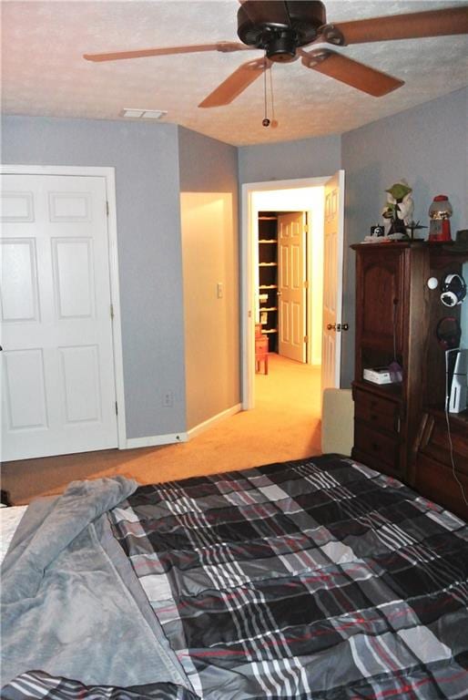 carpeted bedroom featuring ceiling fan and a textured ceiling