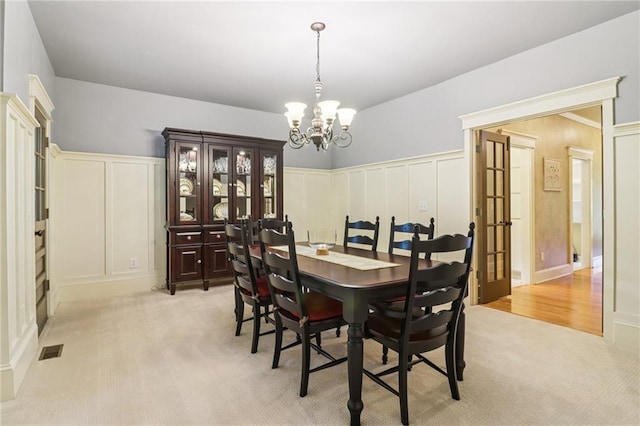 150 Henderson Farm Dr, Woodstock, GA 30188 - dining space with a chandelier, a decorative wall, light carpet, and a wainscoted wall