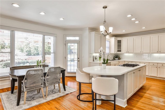 389 Mill Creek Bnd NE, Atlanta, GA 30307 - kitchen featuring crown molding, an inviting chandelier, stainless steel gas cooktop, light countertops, and tasteful backsplash