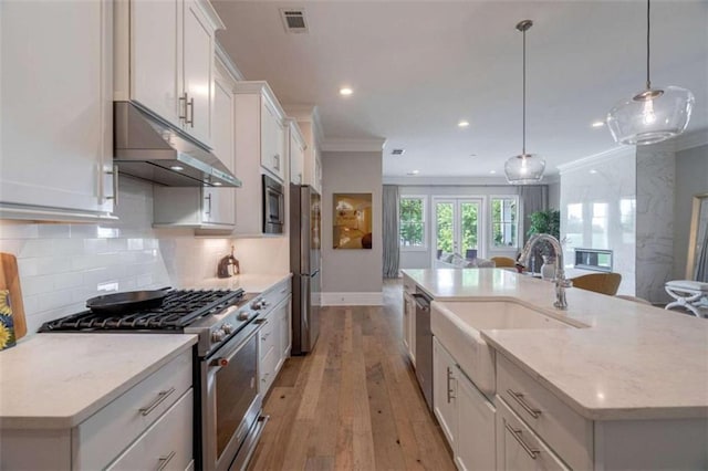 2010 Georgia Club Dr, Statham, GA 30666 - kitchen with under cabinet range hood, stainless steel appliances, light wood-type flooring, a center island with sink, and white cabinets