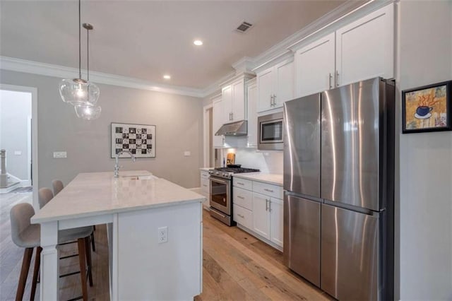 2010 Georgia Club Dr, Statham, GA 30666 - kitchen with stainless steel appliances, under cabinet range hood, white cabinets, a kitchen island with sink, and crown molding