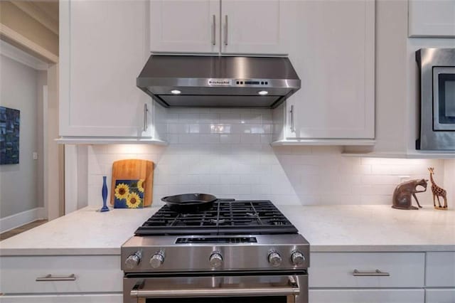 2010 Georgia Club Dr, Statham, GA 30666 - kitchen featuring stainless steel appliances, exhaust hood, backsplash, and white cabinetry