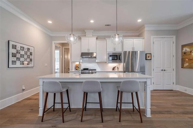 2010 Georgia Club Dr, Statham, GA 30666 - kitchen with appliances with stainless steel finishes, under cabinet range hood, white cabinetry, light countertops, and a spacious island