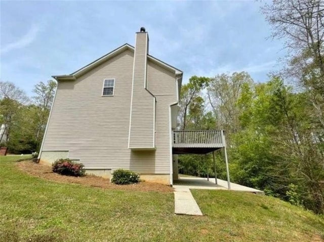 view of side of property featuring a wooden deck, a yard, and a patio area