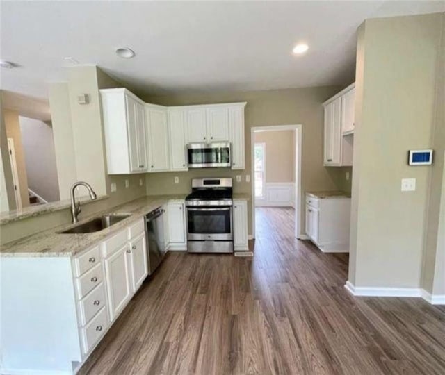 kitchen with dark wood-type flooring, sink, white cabinetry, light stone counters, and appliances with stainless steel finishes