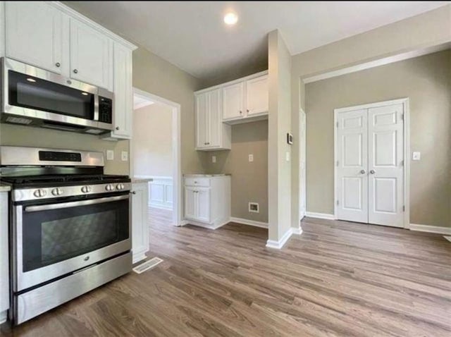 kitchen with white cabinetry, stainless steel appliances, and hardwood / wood-style floors