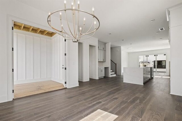 unfurnished living room featuring a notable chandelier, sink, and dark hardwood / wood-style floors