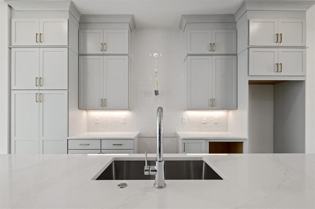 kitchen featuring sink, tasteful backsplash, and light stone counters