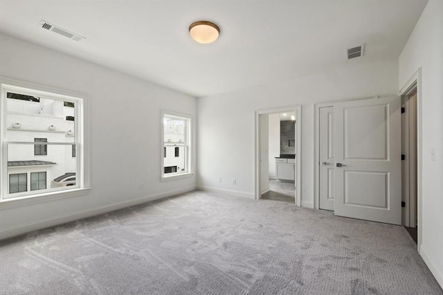 unfurnished bedroom with connected bathroom and light colored carpet