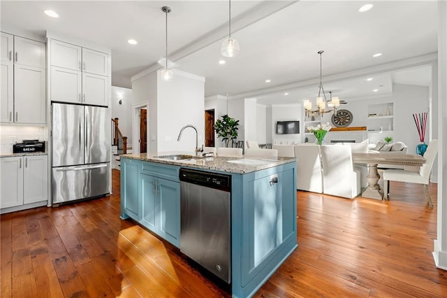 kitchen featuring sink, white cabinetry, pendant lighting, stainless steel appliances, and a kitchen island with sink