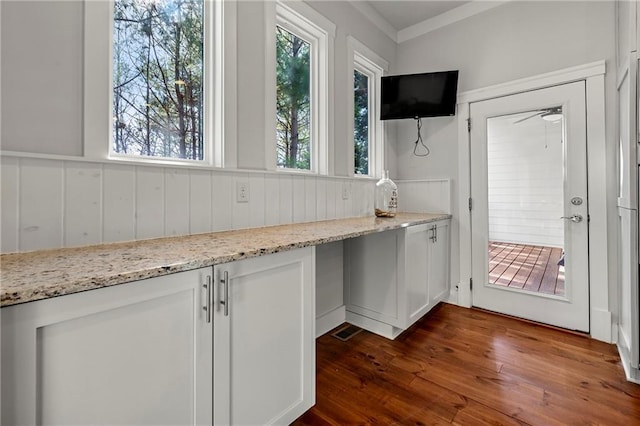 kitchen with white cabinetry, light stone counters, dark wood-type flooring, and ornamental molding