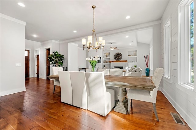 dining space featuring crown molding, hardwood / wood-style flooring, and ceiling fan with notable chandelier