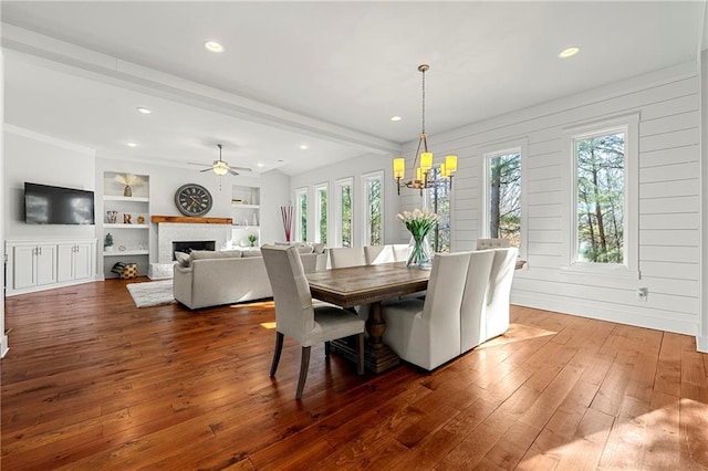 dining space featuring ceiling fan with notable chandelier, built in features, dark hardwood / wood-style floors, and beamed ceiling