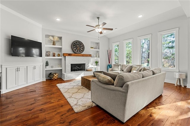 living room with ceiling fan, plenty of natural light, dark hardwood / wood-style floors, and built in features