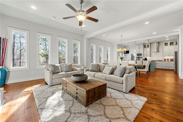 living room with wood-type flooring and ceiling fan with notable chandelier