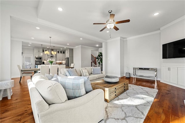 living room featuring ceiling fan with notable chandelier, ornamental molding, and dark hardwood / wood-style floors