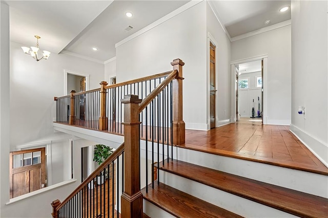 staircase with crown molding, a chandelier, and hardwood / wood-style flooring