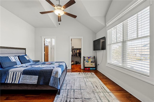 bedroom with ceiling fan, vaulted ceiling, dark hardwood / wood-style floors, a walk in closet, and a closet