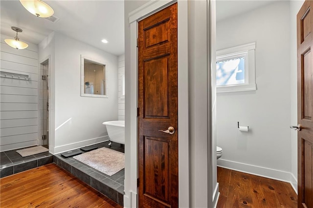 bathroom featuring hardwood / wood-style flooring, a shower, and toilet