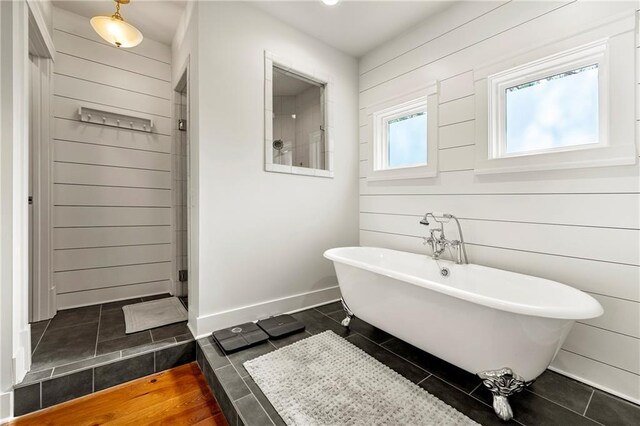 bathroom featuring independent shower and bath, tile patterned floors, and wood walls