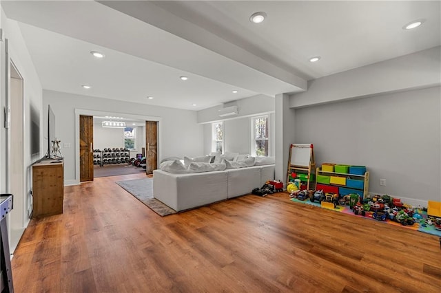 recreation room featuring hardwood / wood-style flooring and an AC wall unit