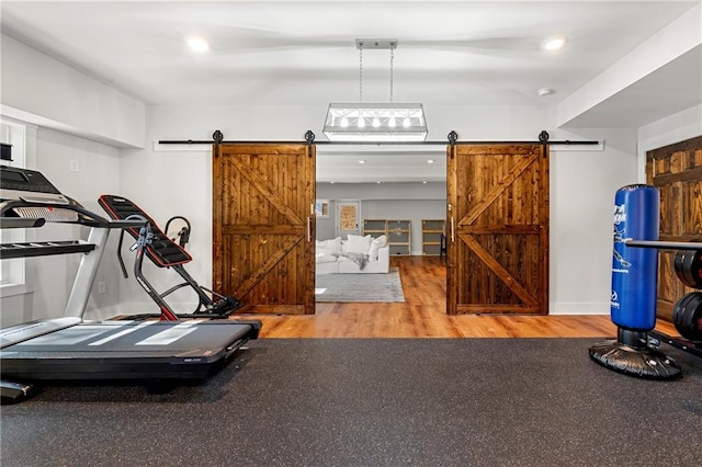 workout area featuring wood-type flooring and a barn door