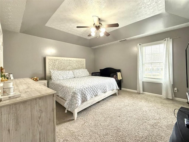 bedroom with baseboards, visible vents, light colored carpet, and a textured ceiling