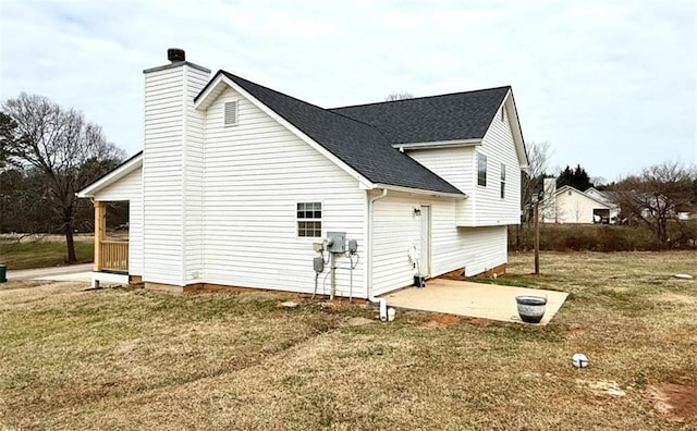 view of home's exterior featuring roof with shingles, a chimney, a patio area, and a lawn