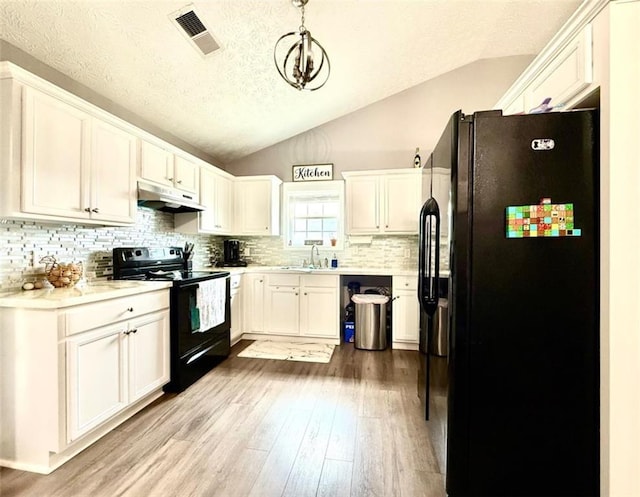 kitchen with visible vents, a sink, under cabinet range hood, black appliances, and vaulted ceiling
