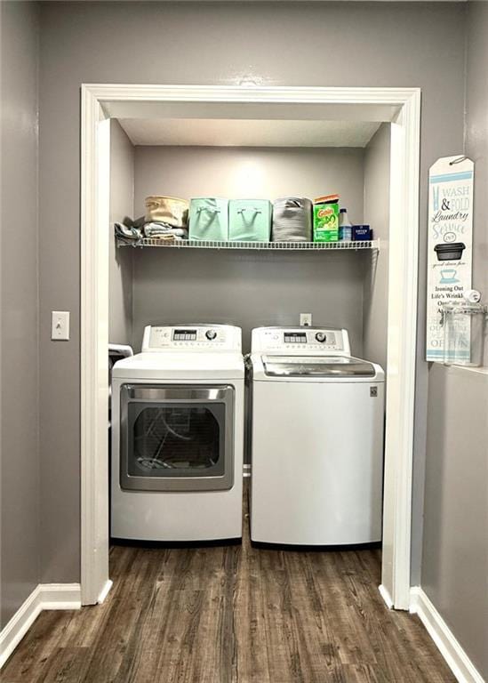 clothes washing area with baseboards, dark wood-style flooring, independent washer and dryer, and laundry area
